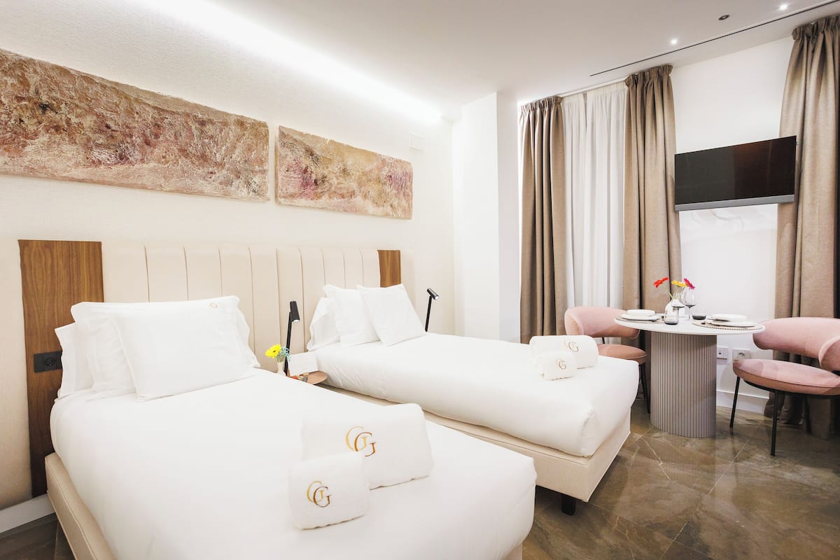 Habitación de hotel con dos camas, una mesa de comedor y un televisor.
