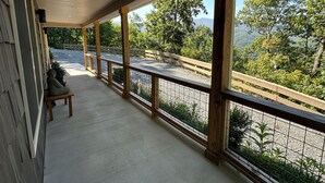 A covered porch with a view of a mountainous landscape.