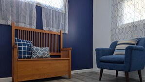 A room with a wooden bench and a blue armchair, both with patterned cushions.