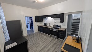 A modern kitchen with dark cabinets, a stainless steel range, and a wooden countertop.