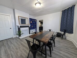 Un comedor con una mesa larga y sillas, una chimenea y un estante azul.