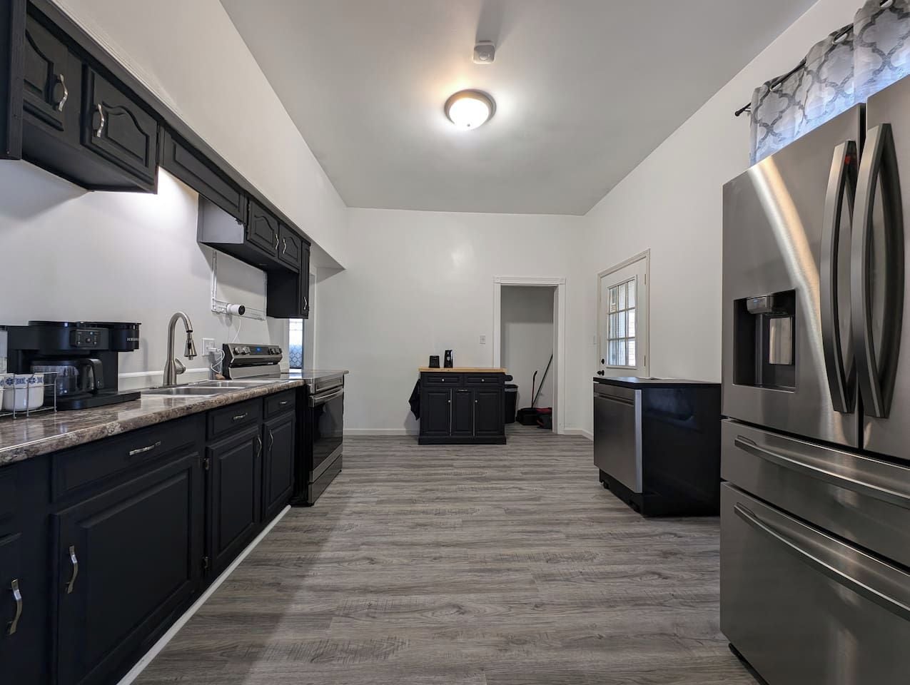 A modern kitchen with dark cabinetry, stainless steel appliances, and a central island.