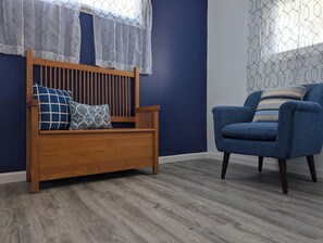 A room with a wooden bench, a blue armchair, and a patterned pillow. - 6BR Home | Sleeps 12+ | Fenced Yard + Pets Welcome (Evansville)