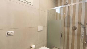 A modern bathroom with a glass-enclosed shower, a bidet, a toilet, and a sink.