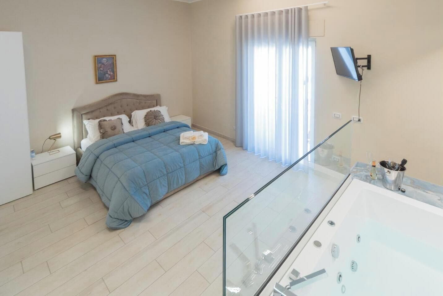 Une chambre à coucher comprenant un lit, une table de chevet, une lampe et un téléviseur fixé au mur.