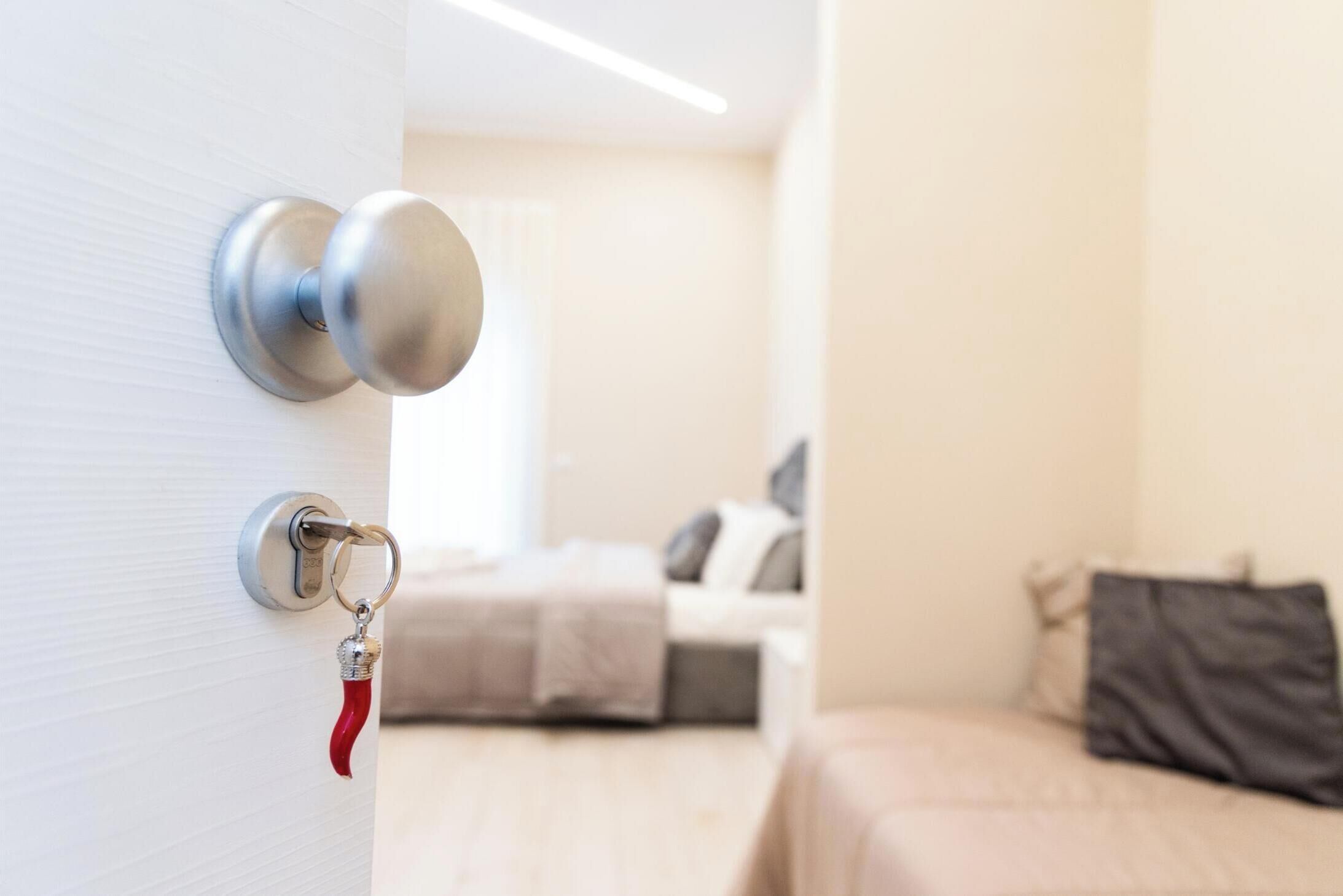 Una habitación de hotel con cama, mesita de noche y una puerta con llavero.