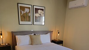 A neatly made bed with white linens and folded towels, two bedside lamps, and framed botanical prints on the wall. - Tranquil 2BR Penthouse Petralona (Athina)