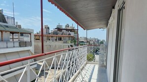 A balcony with a white railing, a wooden table, and a potted plant. - Tranquil 2BR Penthouse Petralona (Athina)