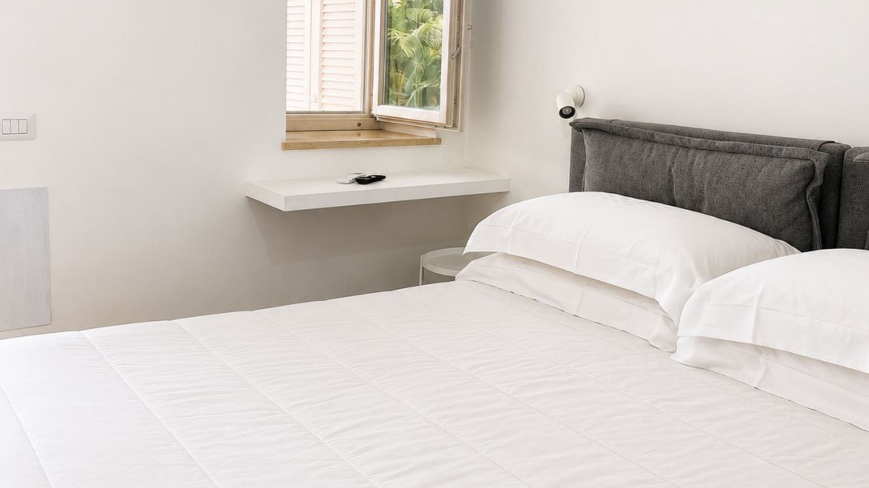 Comfortable king-size bedroom with air conditioning, workspace, natural light, and premium bedding for a restful stay in Capri.