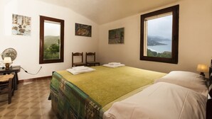 Una camera da letto con un letto, due poltrone, una scrivania con una lampada e opere d'arte alle pareti.