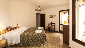 Una camera da letto con un letto, una sedia, una scrivania con una lampada e una finestra.