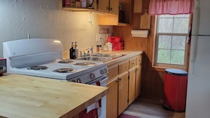 Une cuisine avec des meubles de rangement en bois, une cuisinière, un évier et un réfrigérateur.