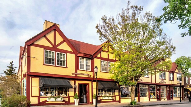 A traditional building with a sign reading "KITCHEN & HOME" on the ground floor, featuring large windows and a red roof.