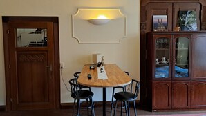 A dining area with a wooden table, four chairs, a wall-mounted light fixture, and a cabinet with glass doors.