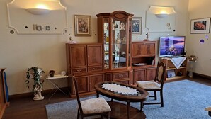 A living room with a wooden cabinet, two chairs, a round coffee table, and a television.