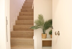 Staircase with a door and potted plants on either side.