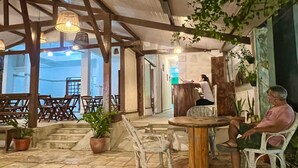 An outdoor patio area with stone flooring, wooden furniture, and hanging lights.