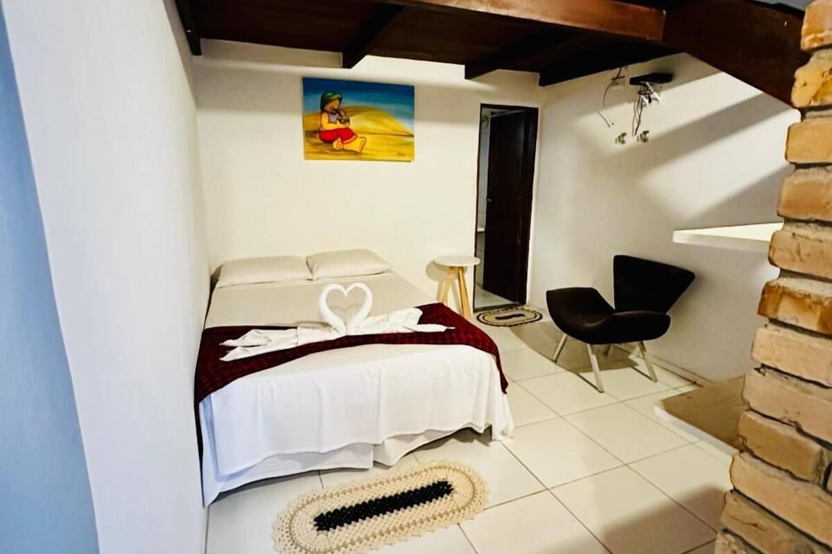 Un dormitorio con una cama, un escritorio pequeño, una silla, una alfombra y un cuadro en la pared.