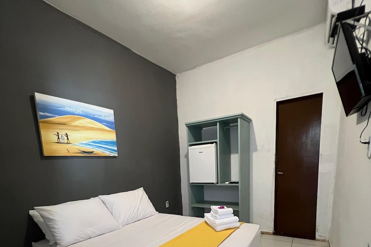 Habitación de hotel con cama, un plaid amarillo, un cuadro, un armario y una puerta.