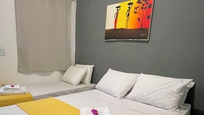 A hotel room with two beds, a painting on the wall, and towels on the bed.