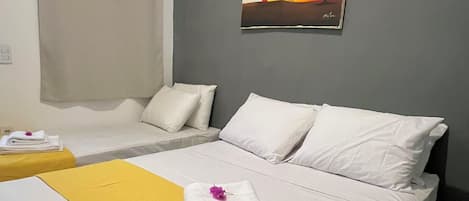 A hotel room with two beds, a painting on the wall, and towels on the bed.