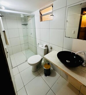 A bathroom with a glass-enclosed shower, a toilet, a sink, and a mirror. - Pousada Vila do Sol (Jijoca de Jericoacoara)