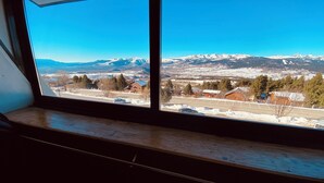 A window with a view of a snowy landscape, including mountains and a town. - Apartment facing the mountains -la Belle étoile (Eyne)