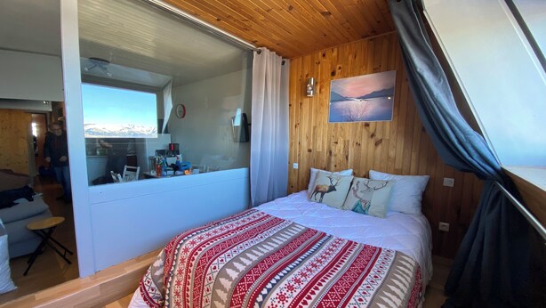 A cozy bedroom with a large bed, a wooden ceiling, a window with curtains, and a painting on the wall. - Apartment facing the mountains -la Belle étoile (Eyne)