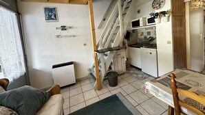 Een knus woongedeelte met een keuken, een trap en een eethoek.