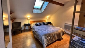Een slaapkamer met dakraam, een bed, een stoel, nachtkastjes en een boekenkast.