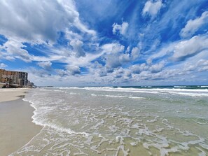 A beach with waves, a pier, and buildings in the background. - Spacious 3-bedroom ocean front condo with fitness room, in Daytona Beach Shores! (Daytona Beach)
