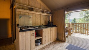 Cucina di una casetta in legno con un fornello, un lavandino e mensole.