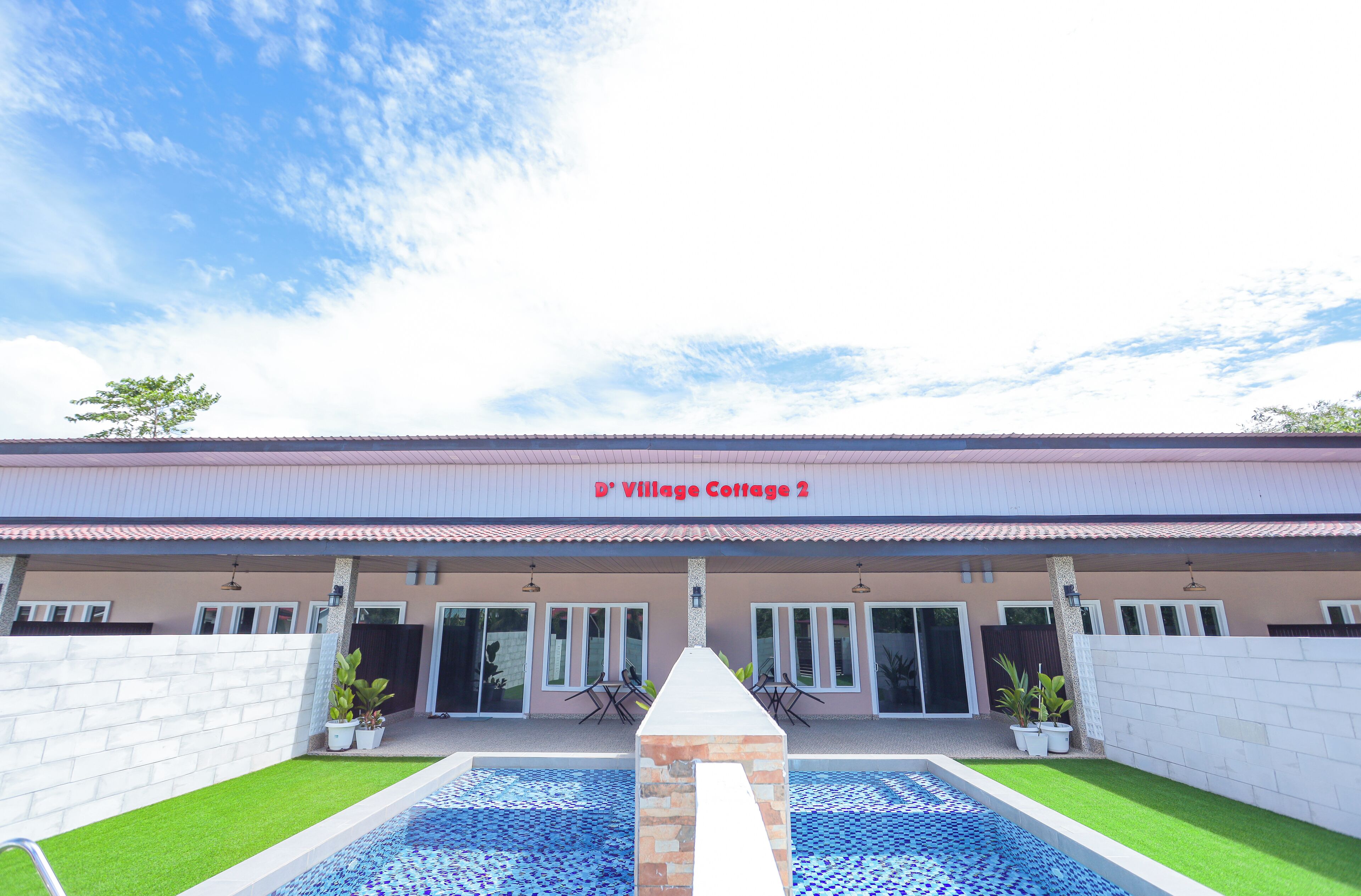 Un bâtiment à deux étages, doté d’un toit en tuiles et d’une enseigne indiquant « D’Village Cottage 2 ».