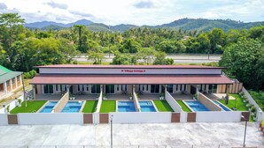 A modern building with a red roof, labeled "D' Village Cottage 2," featuring multiple swimming pools and a covered patio area. -  D' Village Cottage 2 – Private Pool Villas (Langkawi)