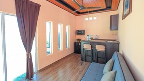A room with a sofa, two chairs, a small kitchen area with a microwave, and a ceiling fan. -  D' Village Cottage 2 – Private Pool Villas (Langkawi)