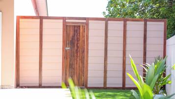 A wooden gate with a metal handle, a white fence, and a green lawn.