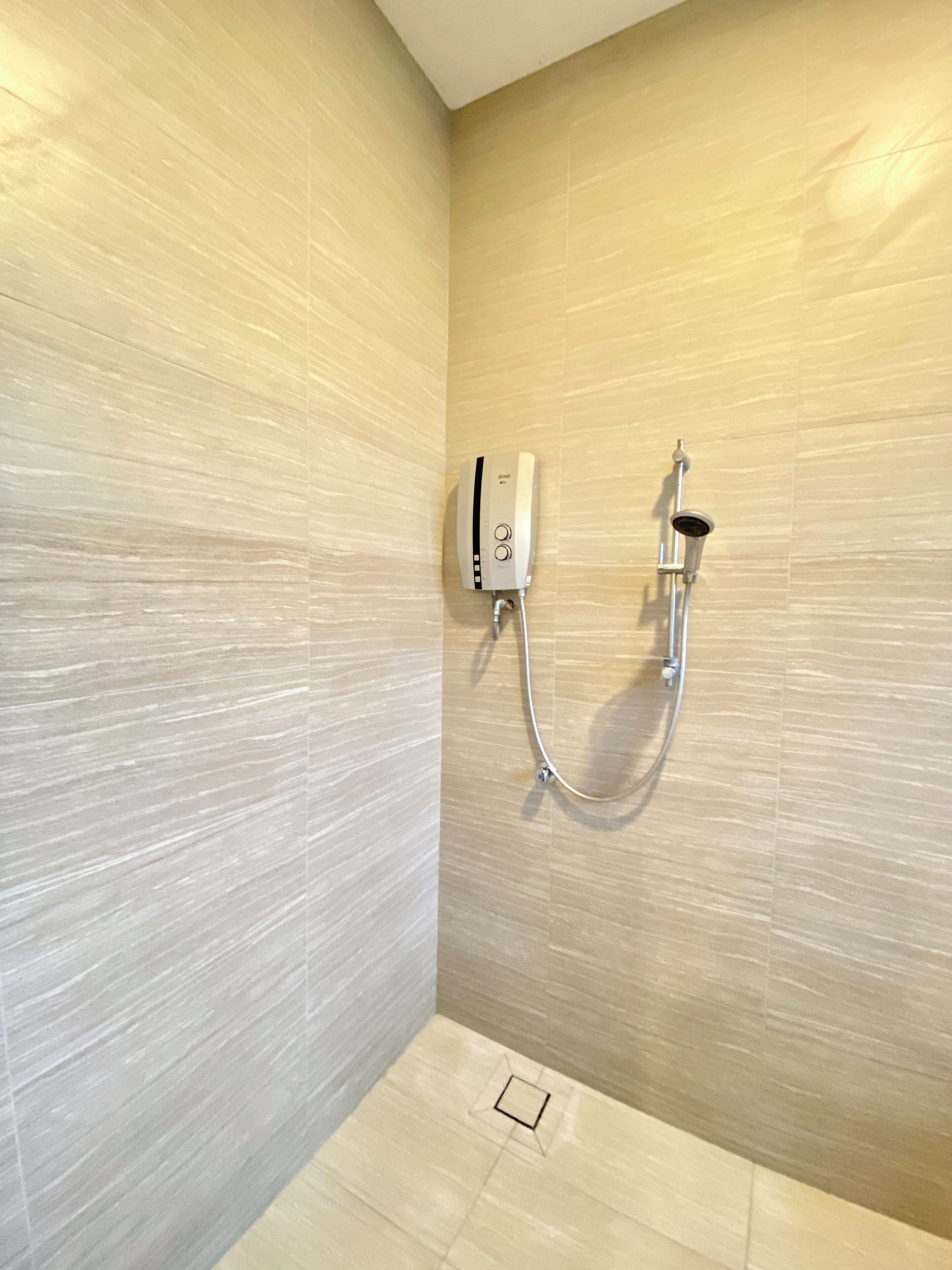 A shower area with a control panel and a handheld showerhead mounted on the wall.