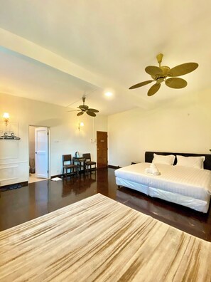 Ein geräumiges Schlafzimmer mit einem großen Bett, einem Deckenventilator und Holzboden.