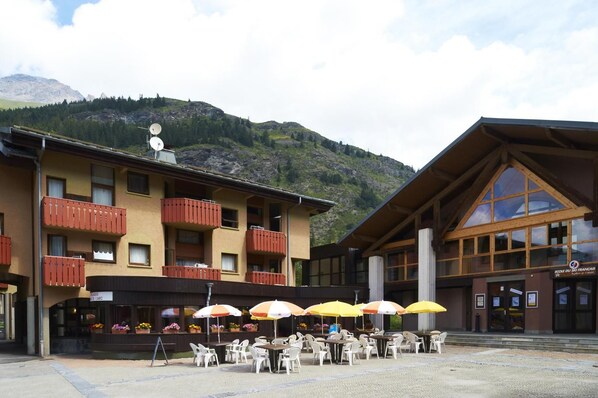 A hotel with outdoor seating and a mountain backdrop.