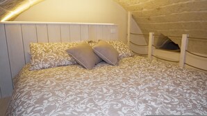 A bedroom with a vaulted ceiling, a bed with patterned bedding, and a headboard against a brick wall. - La mia Volta in Ostuni (Ostuni)