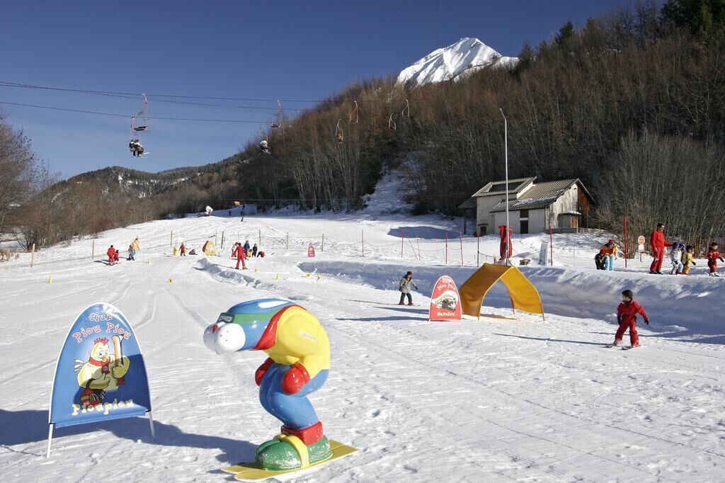 A snowy ski slope with a colorful inflatable duck, a ski lift, and a mountain in the background.