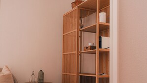Een houten boekenplank met manden en een klein rond tafeltje met glazen.