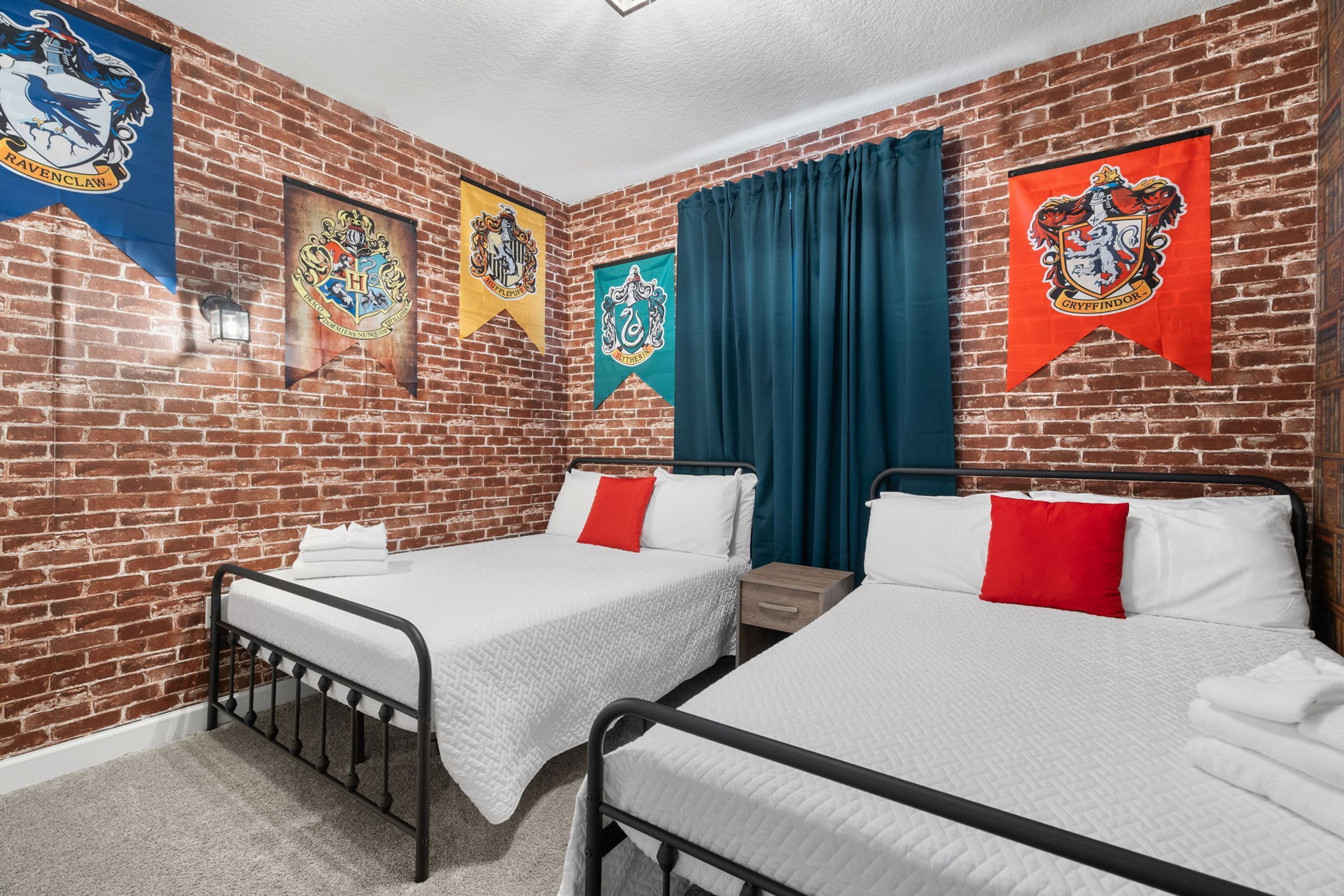 A room with two beds, brick walls, and banners of Hogwarts houses.