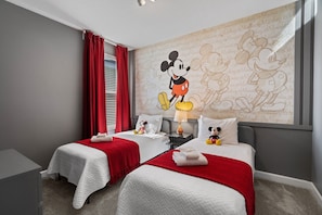 A hotel room with two beds, red curtains, a Mickey Mouse mural, and a lamp. - Gorgeous 6-bedroom House With Private Pool (Davenport)