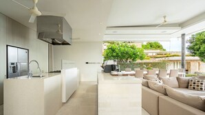 A modern kitchen with a central island, built-in appliances, and a dining area with a sofa and chairs. - Samujana Villas - Villa Karawek (Bo Put)