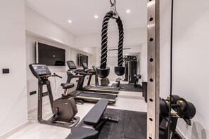A modern home gym with treadmills, a stationary bike, and weightlifting equipment.