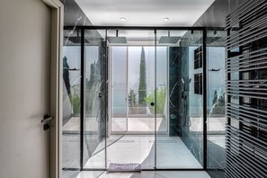 Una puerta de cristal moderna que da a un balcón con vistas a un árbol alto y un edificio.
