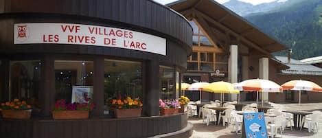 Un restaurant appelé « VVF Villages Les Rives de l’Arc » qui dispose d’une terrasse et offre une vue sur les montagnes.