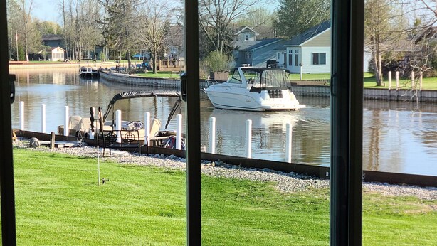 A view through a window of a grassy area with a dock and a boat.