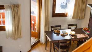 A dining area with a wooden table and chairs, a laptop on a small table, and a staircase leading to another level. - Wifi, 300m from shops, parking, tv, ski locker, 35m², Val Cenis (Val Cenis)
